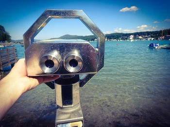 Close-up of hand holding camera against cityscape