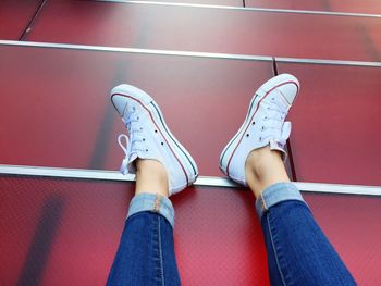 Low section of woman wearing shoes while sitting tiled floor