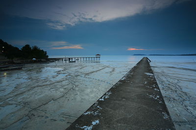 Pier over sea against sky during sunset