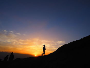Silhouette man standing on mountain against sky during sunrise