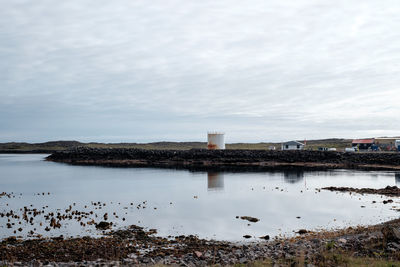 Flock of birds by sea against sky