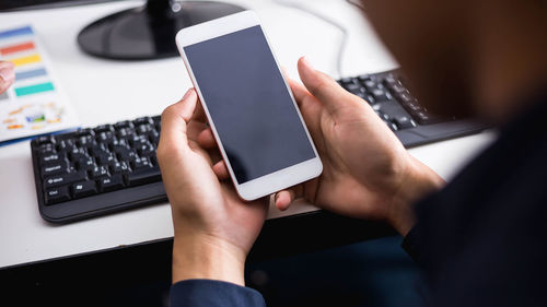 Midsection of man using mobile phone on table