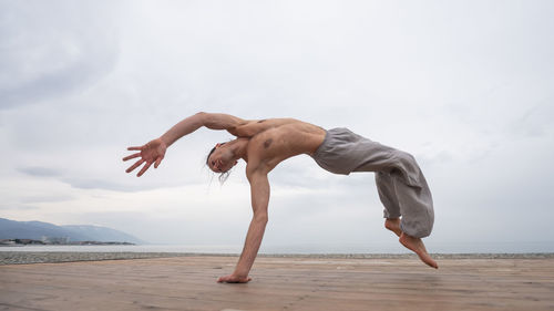 Man backflipping against cloudy sky