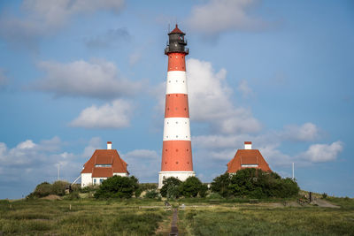 Lighthouse by building against sky