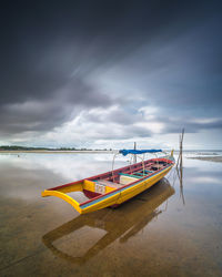 Boat moored on beach against sky