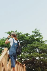 Rear view of woman standing by plants against sky