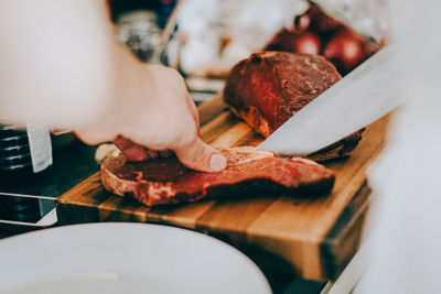 Cropped image of person cutting meat