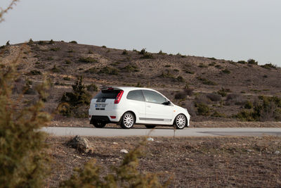 Side view of car on mountain road against clear sky