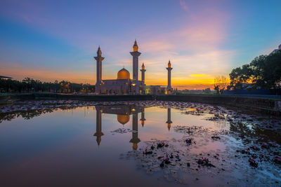 Reflection of illuminated mosque on lake during sunset