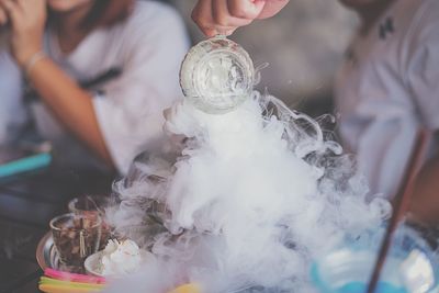 Cropped fingers of person pouring liquid on food