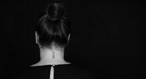 Rear view of woman with hair bun against black background