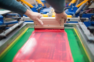 Cropped hands of man with paint on machinery in factory