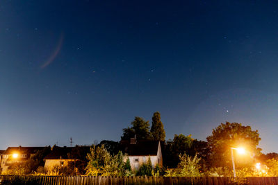 Illuminated house on field against sky at night