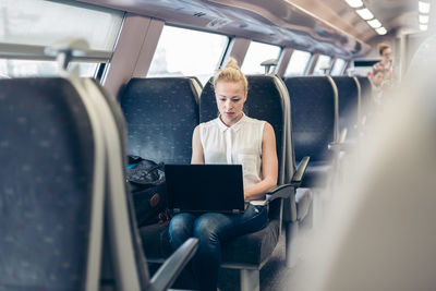 Rear view of man using mobile phone while sitting in bus