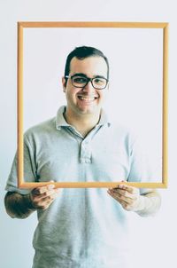 Portrait of young man standing against white background