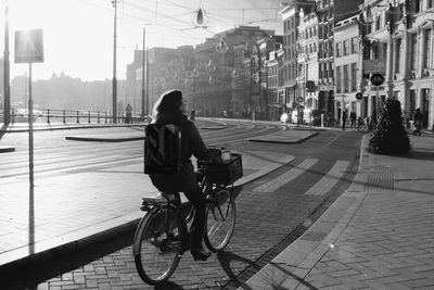 Rear view of man riding bicycles on street in city