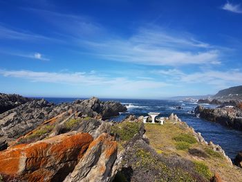 Rock formations by sea against blue sky