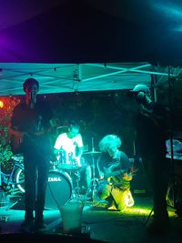 People standing by illuminated lights at music concert