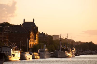 Boats in river against sky during sunset