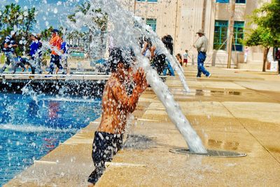 Boy standing by fountain in city