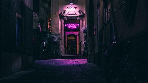 Illuminated alley amidst buildings in city at night