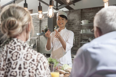 Female chef talking to senior couple in cooking class