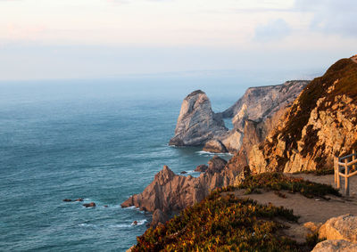 Scenic view of sea by cliff against sky