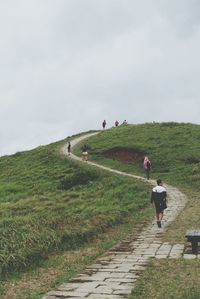 People on hill against cloudy sky