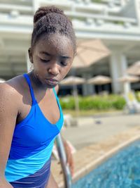 Portrait of young woman standing by swimming pool