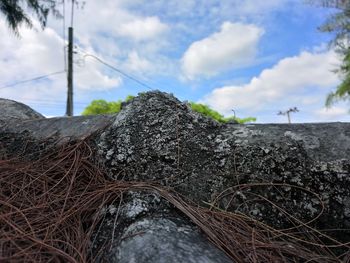 Close-up of rusty metal on field against sky