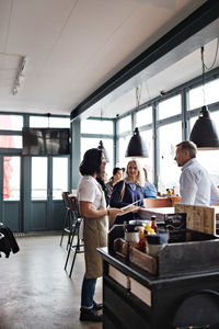 Owner showing menu cards to customers while standing at restaurant