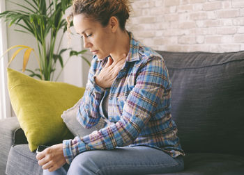 Young man using mobile phone while sitting on sofa at home