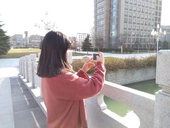 Rear view of woman photographing against sky