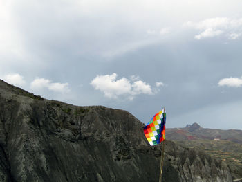 Low angle view of multi colored flag on mountain against sky