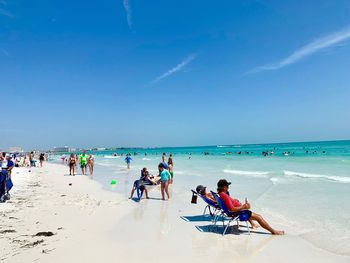 People on beach against blue sky