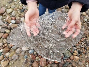 Close up of child's hands holding a clear flat piece of ice found with intricate patterns 