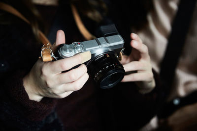 Midsection of woman holding camera while sitting with friend in taxi