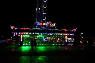 Illuminated ferris wheel against sky at night