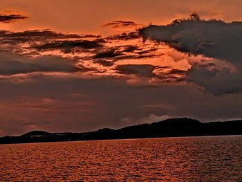 Scenic view of sea against dramatic sky during sunset