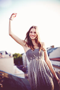 Portrait of a smiling young woman against sky