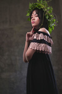 Girl looking away while standing against wall