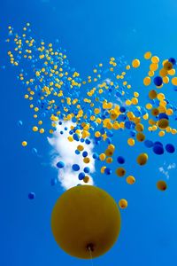 Low angle view of balloons in sea against blue sky