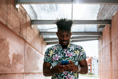 Close-up of african man using smart phone while standing amidst walls