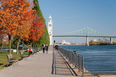 People by river against sky during autumn