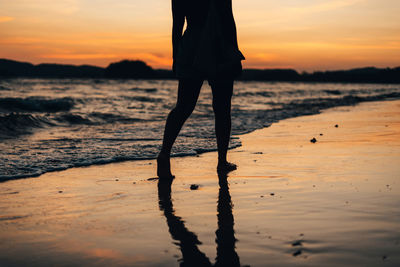 Silhouette woman walking at beach during sunset