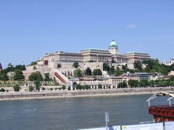 Buildings at waterfront against blue sky