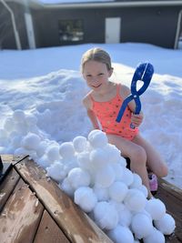 Portrait of a girl in in bathing suit playing in snow making snowballs