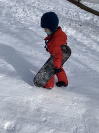 Full length of child on snow covered land with snowboard 