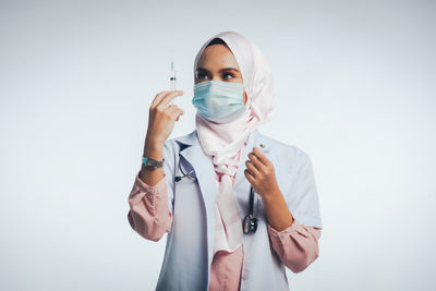 Portrait of young woman standing against white background