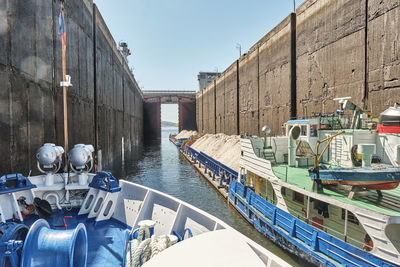 Ships wait for lock chamber gates to fully open.tugboat and barge with sand. shipping lock